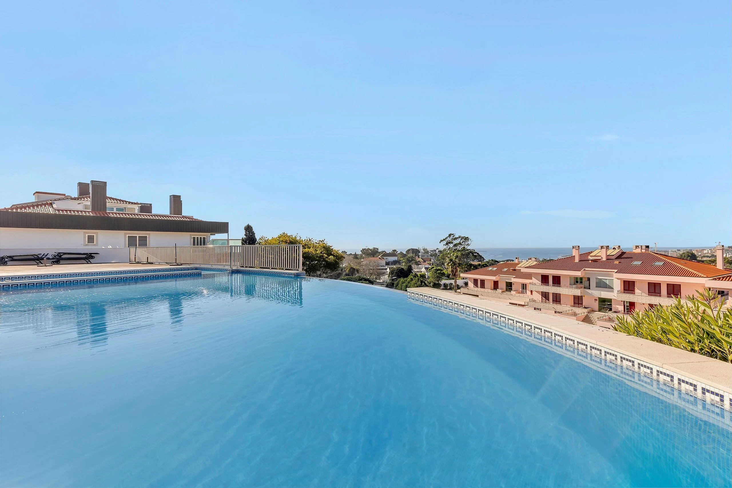 Infinity pool overlooking coastal homes and sea