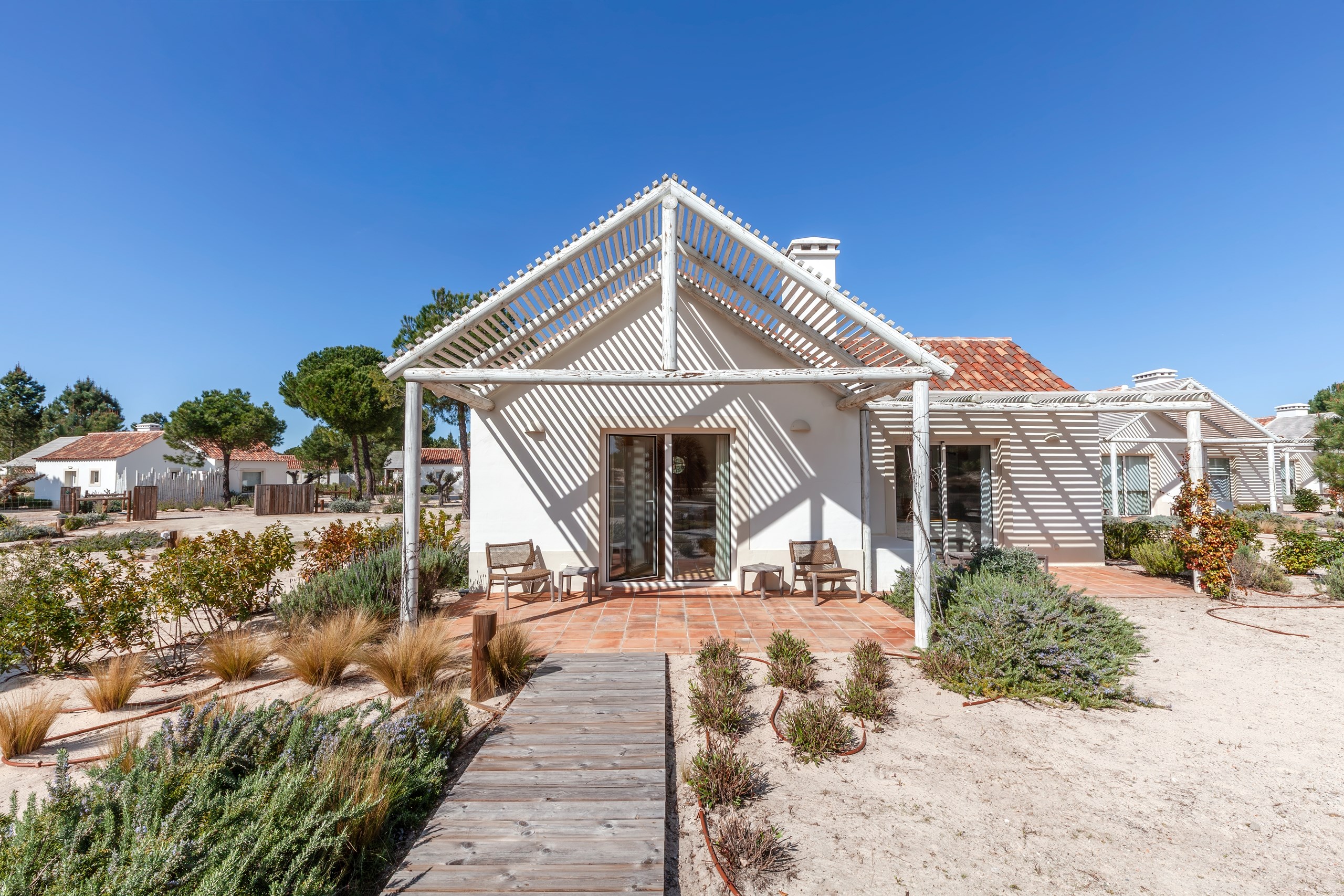 White villa with pergola and sandy garden