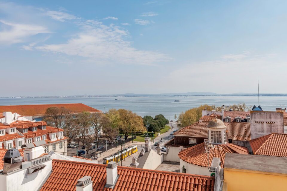 Riverside cityscape with red roofs and yellow tram