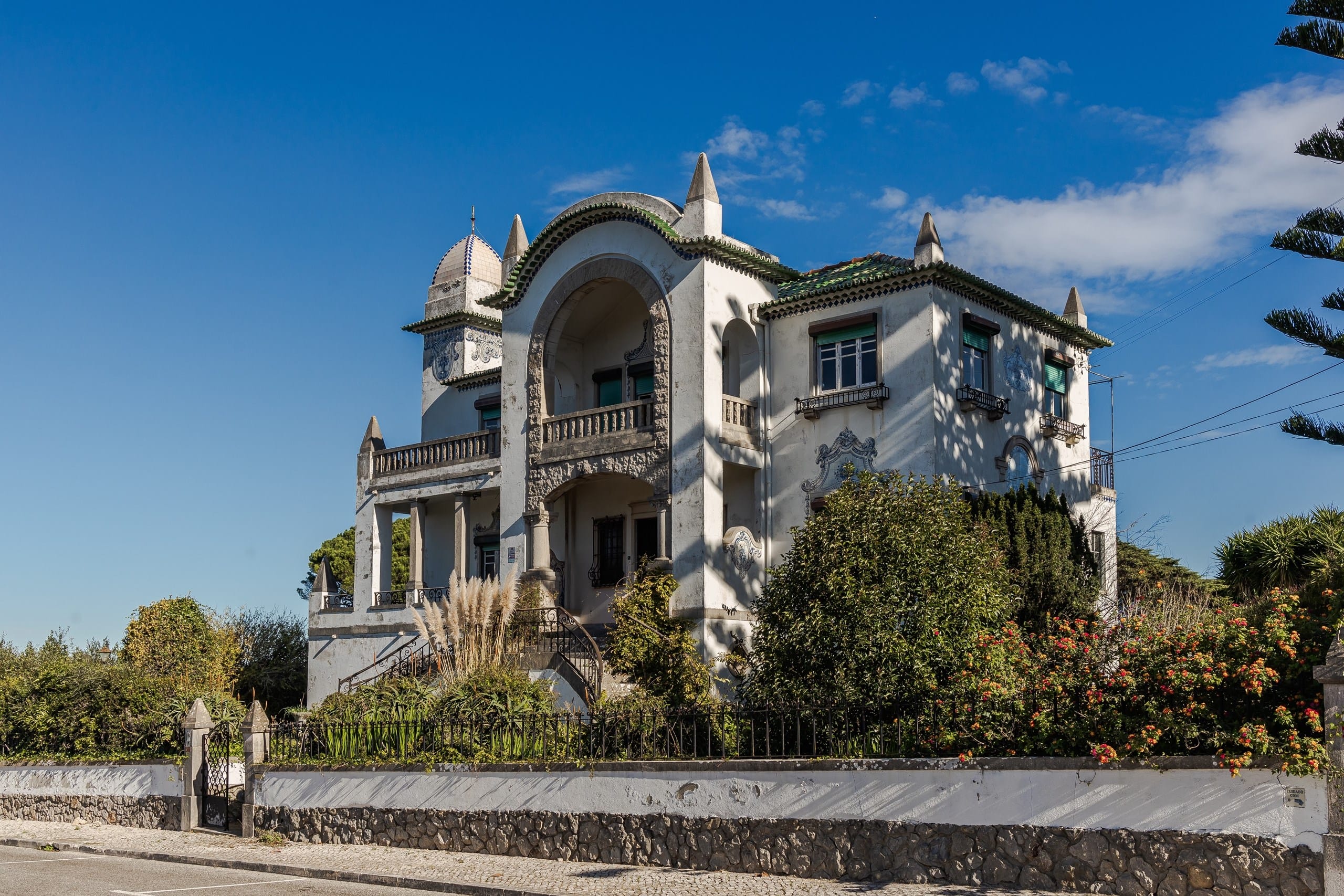 Ornate white villa with arched balcony and garden