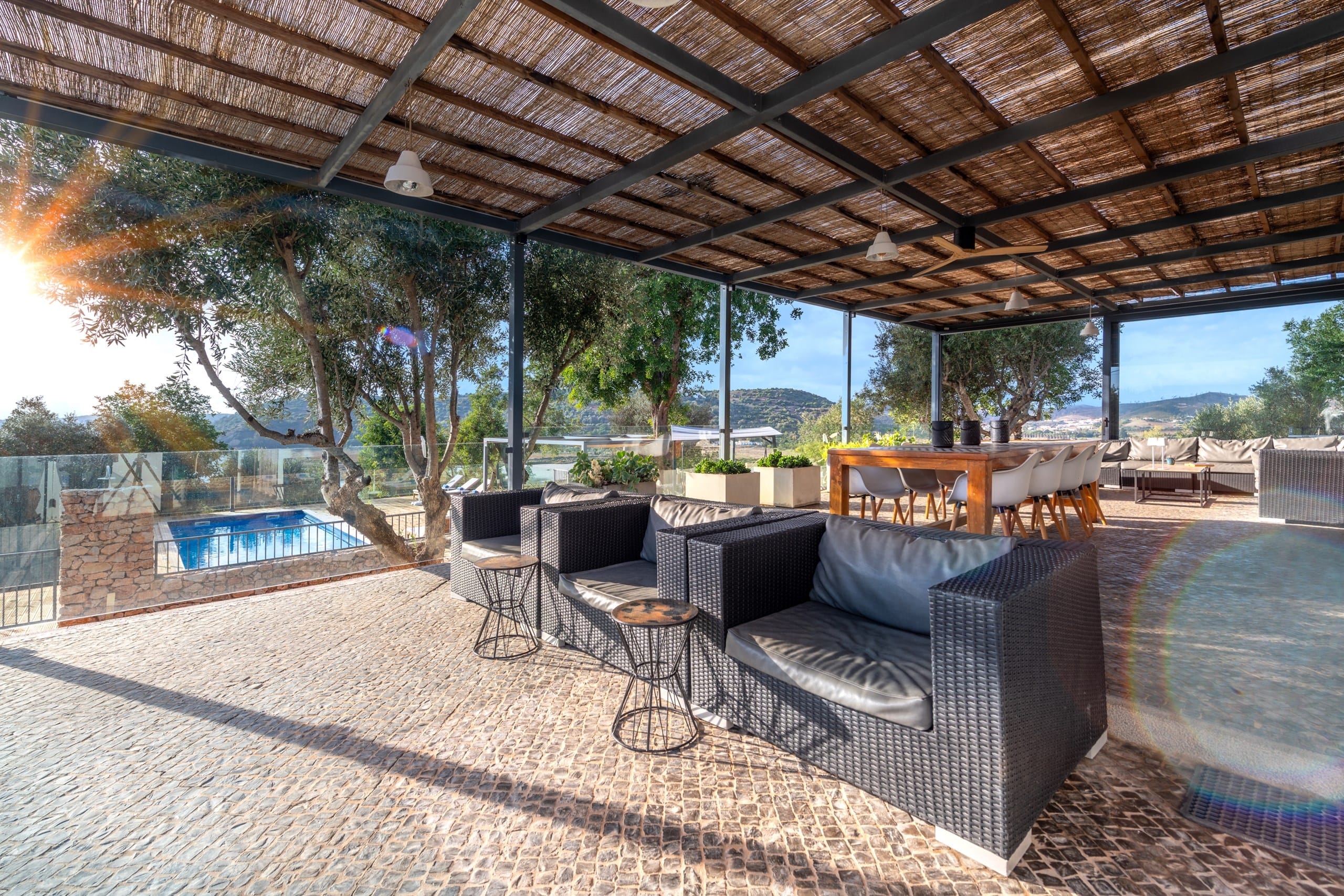 Covered terrace with sofas, pool and hills view