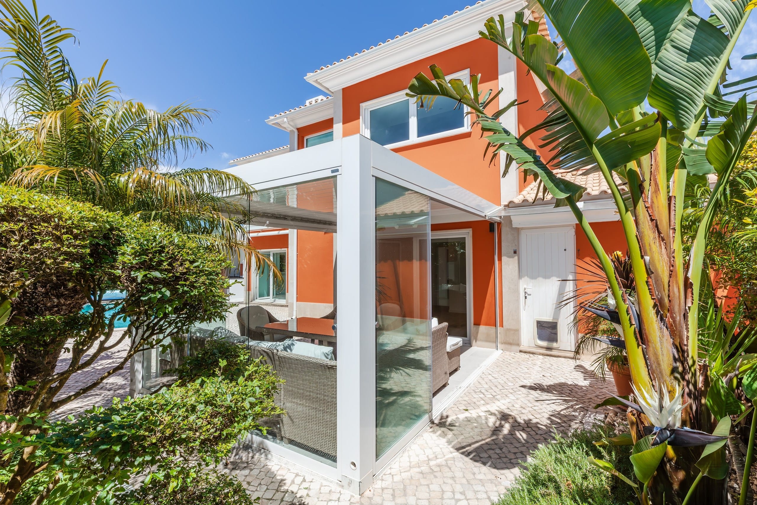 Modern orange villa with glass patio and palms
