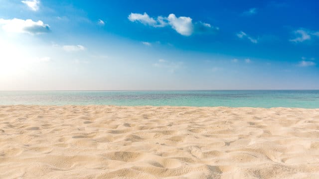 Sunny sandy beach with turquoise sea and blue sky