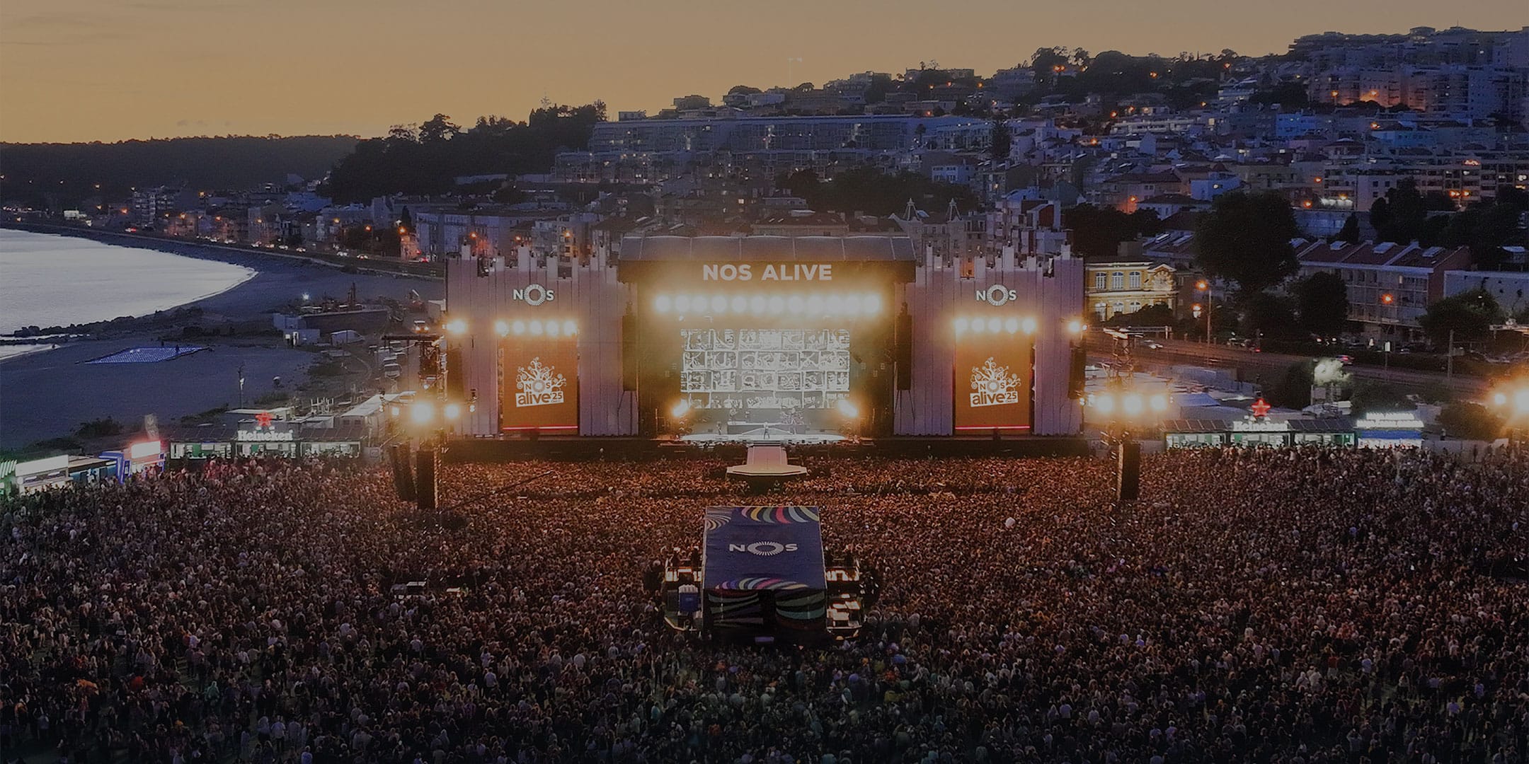 Large seaside music festival crowd at dusk
